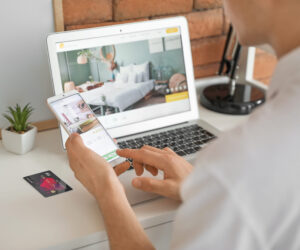 Man with mobile phone booking room in hotel online at home